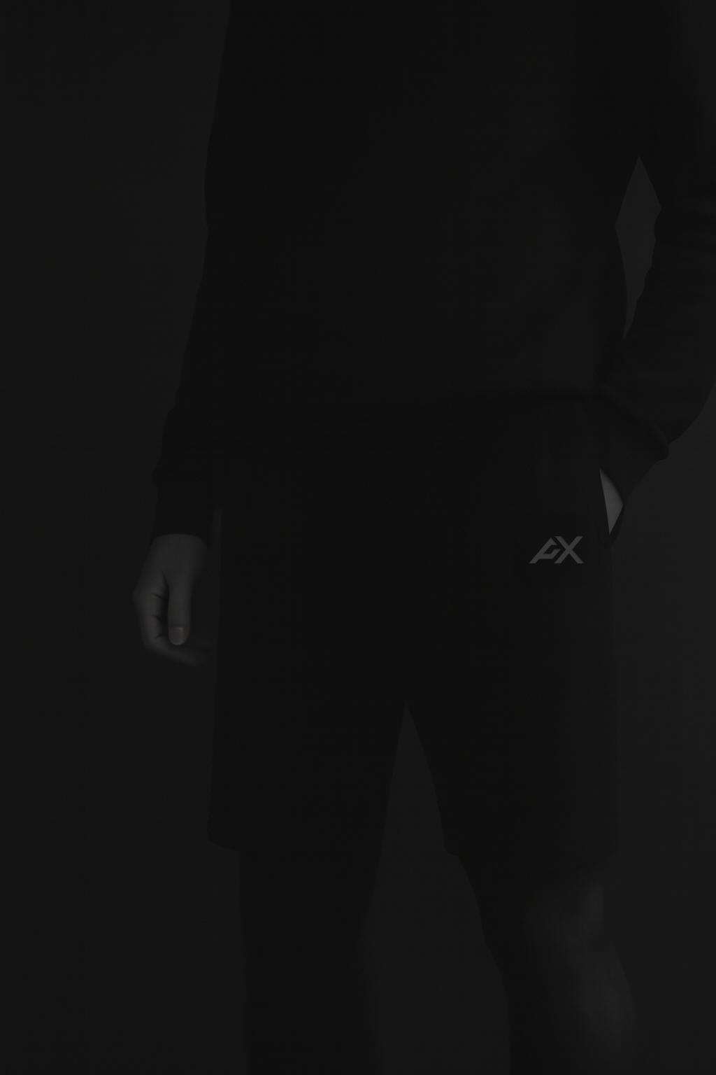 Person wearing a dark suit with a visible brand logo on a black background